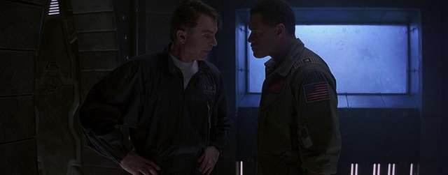 Still from Event Horizon. Laurence Fishburne & Sam Neill stand in a dark, claustrophobic spaceship interior.